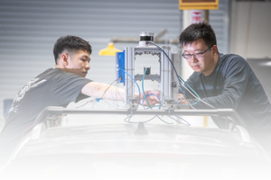 Researcher in a blue lab coat working with engine testing equipment at CE-CERT.