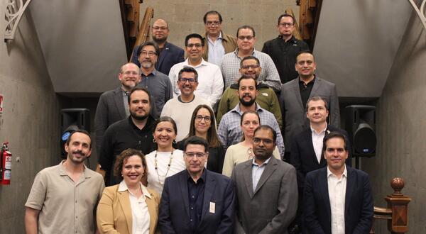 Twenty-two participants from the Binational Working Group on Zero-Emission Vehicles pose on a staircase at the Casa de la Universidad de California in Mexico City.