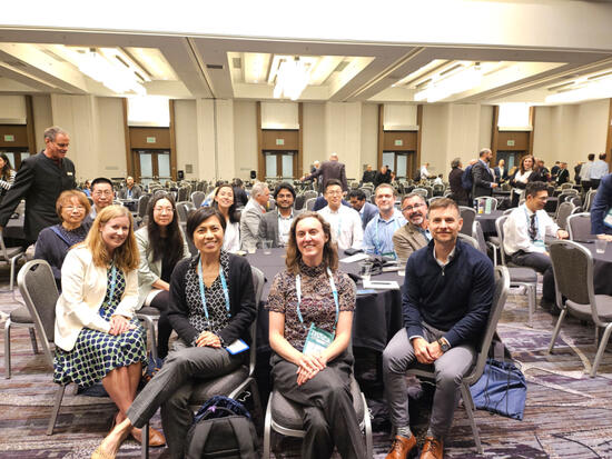 A group of attendees sits around a table in a conference room, smiling for a group photo during the ITSCA 2024 event. Saswat Priyadarshi Nayak, CE-CERT graduate student, is seated among the group.