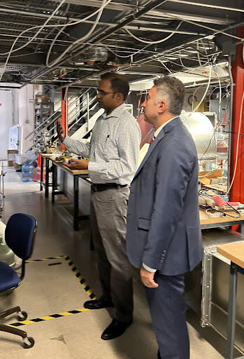  A photo of two men inside a research lab. On the left, Arun Raju is gesturing towards equipment as he gives Prof. İdris Demir (right) a tour of the APL (Atmospheric Processes Laboratory)